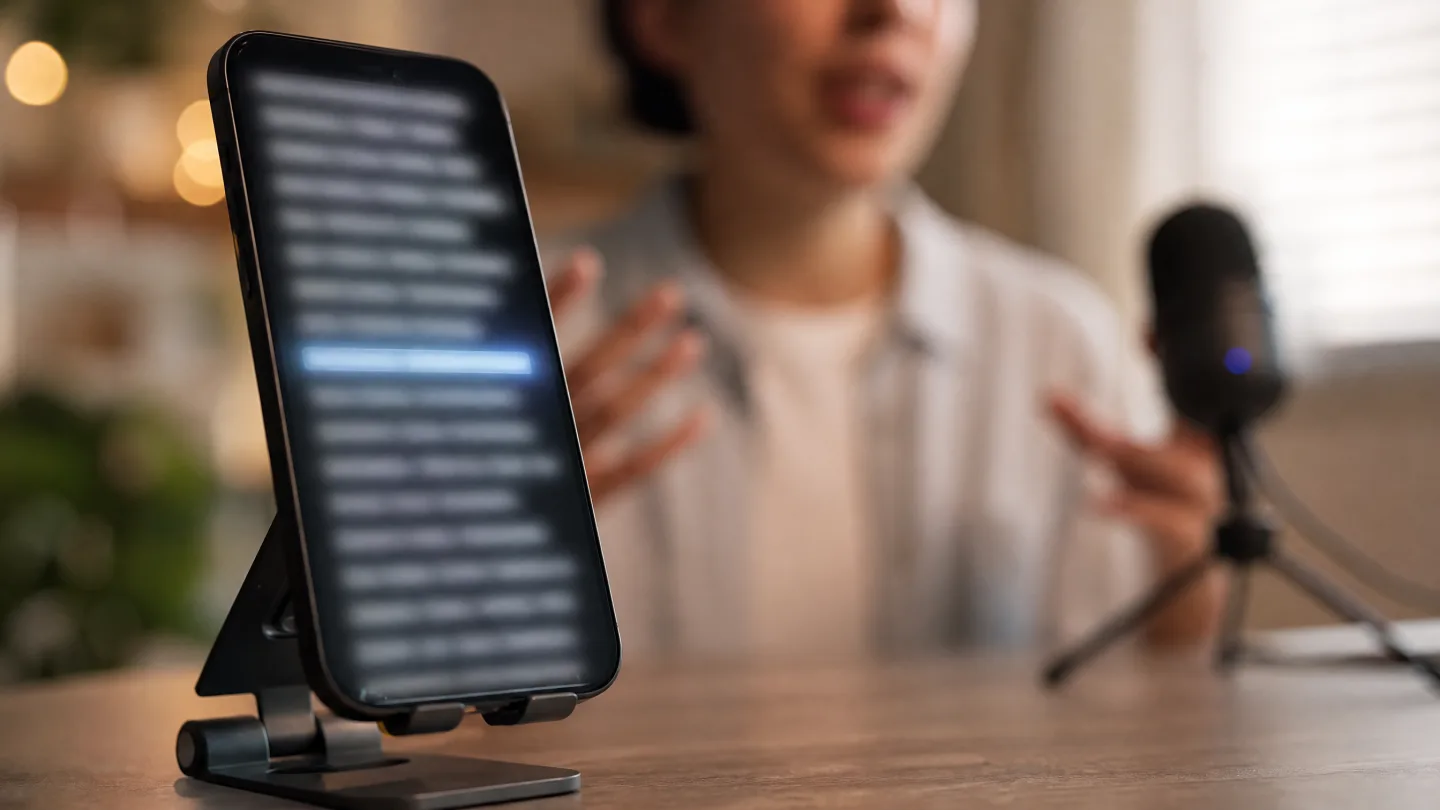 A phone on a stand with the current script line highlighted while a speaker talks behind it